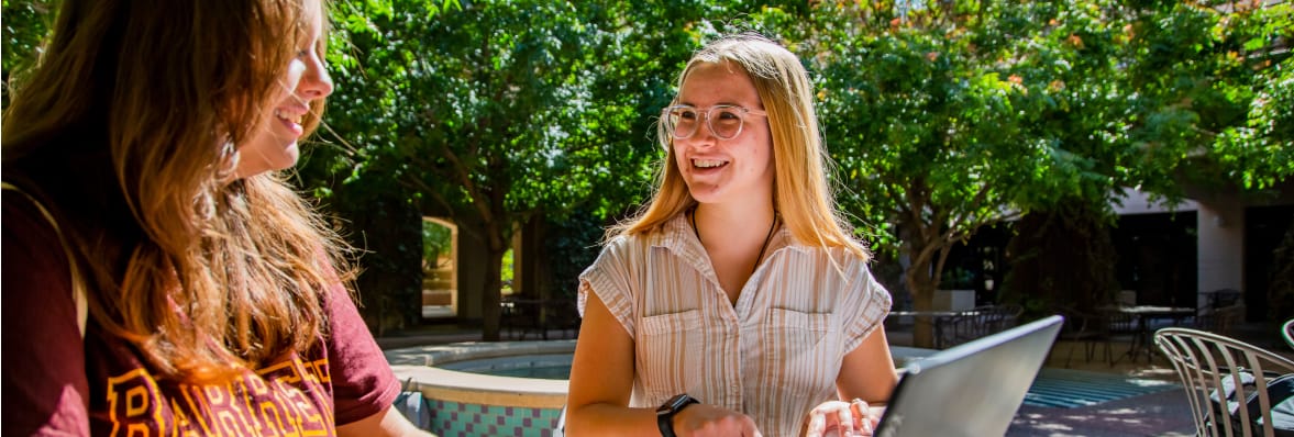 Two ASU students sitting outside and smiling