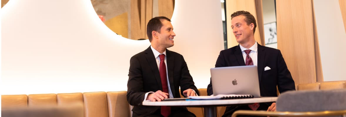 Two businessmen sitting at a table with a laptop