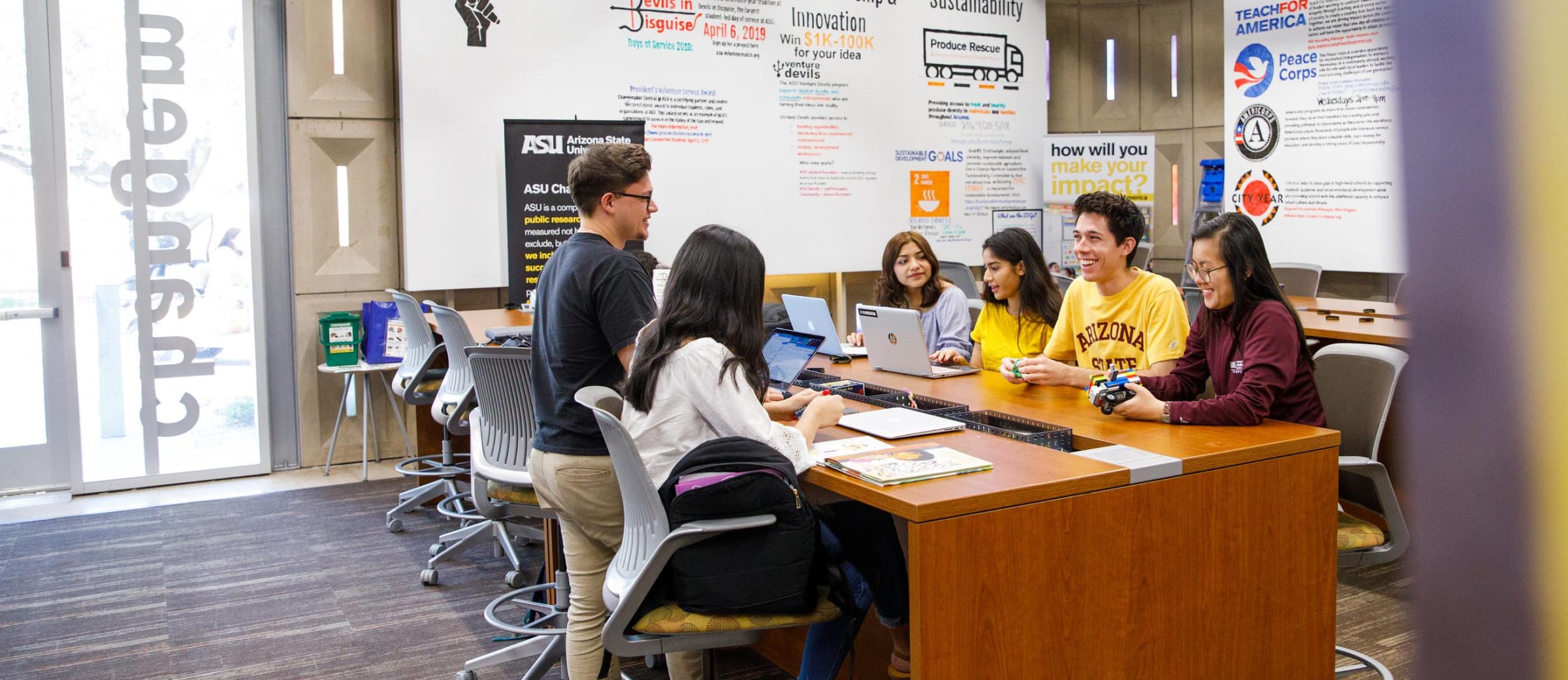 Students sitting at a table with posters around them