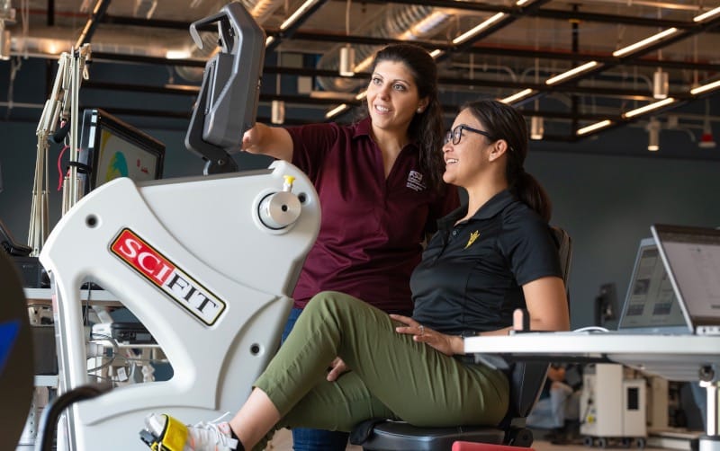 Professor and student working with gym equipment