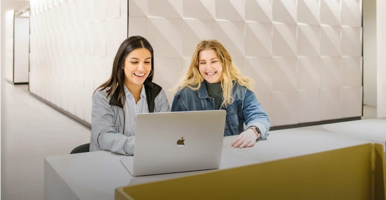 Students smiling and sitting at a desk