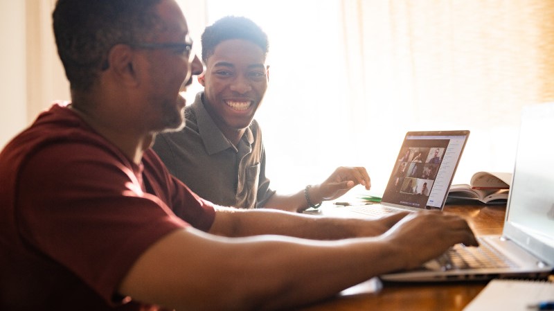 Dad and son sitting together with computers