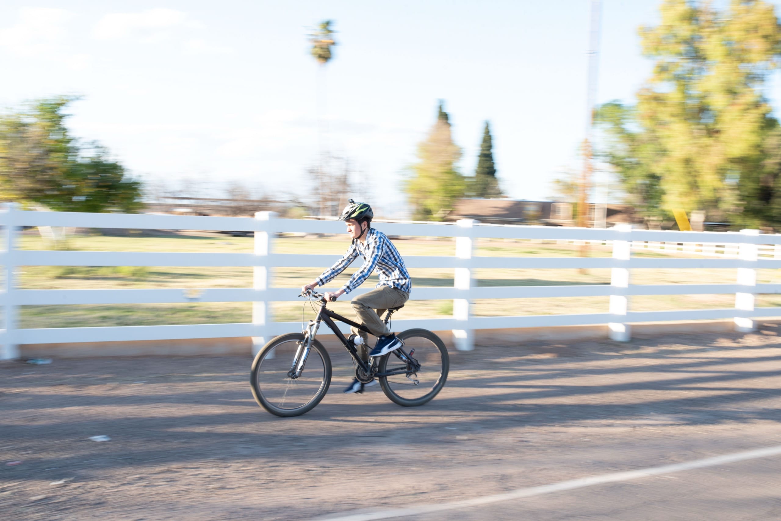 Man riding a bike near a white fence