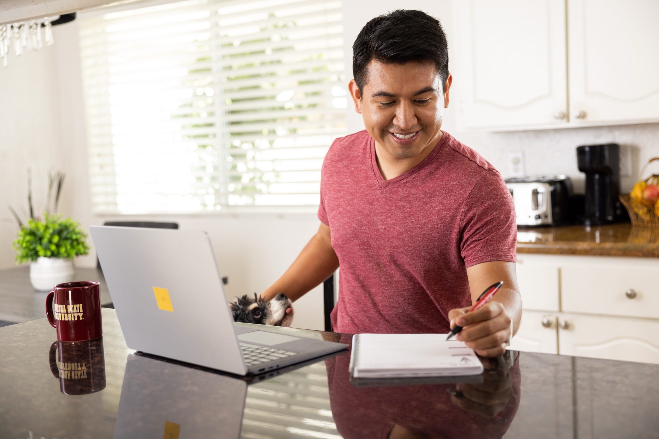 ASU student working on a laptop in his kitchen