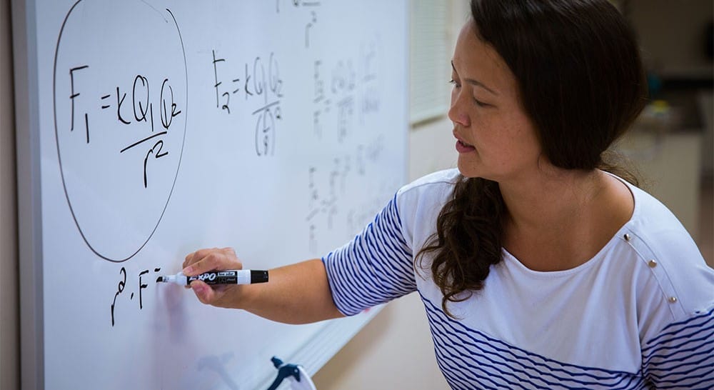 Woman writing equations on a whiteboard