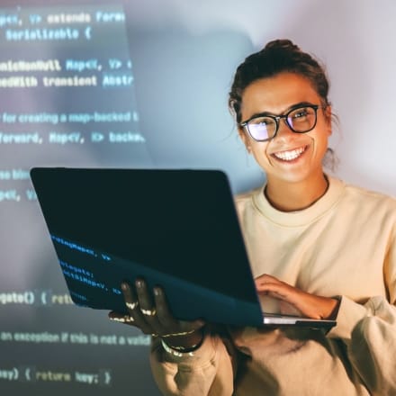 Woman smiling and holding a laptop